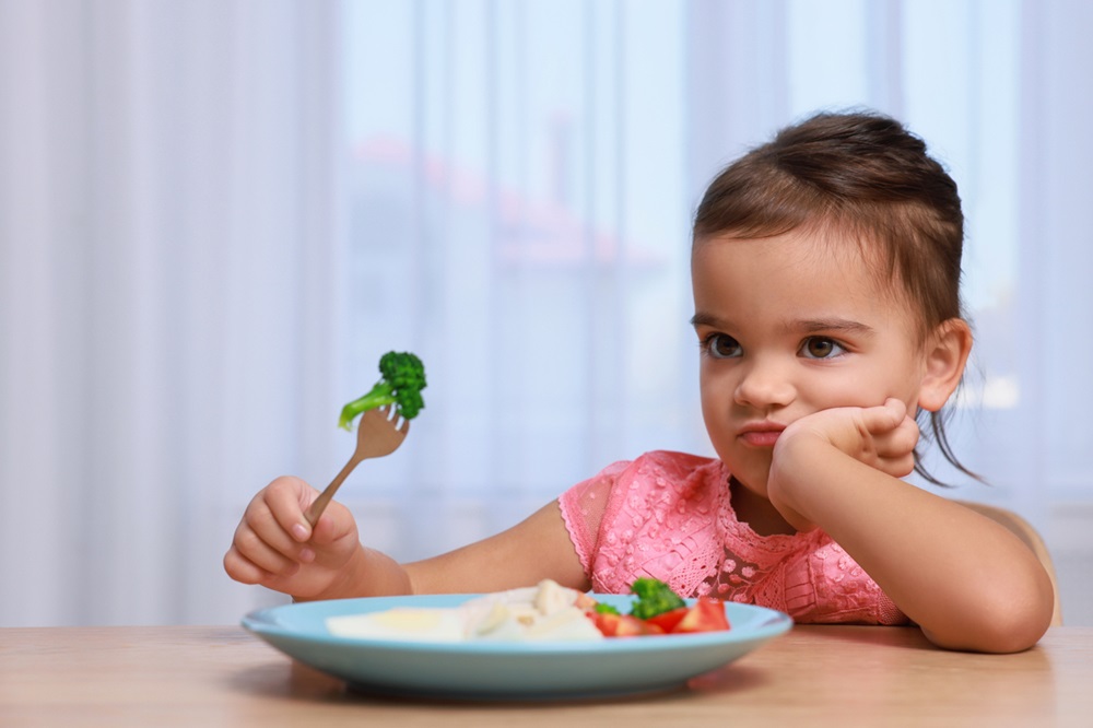 Young girl refusing to eat vegetables